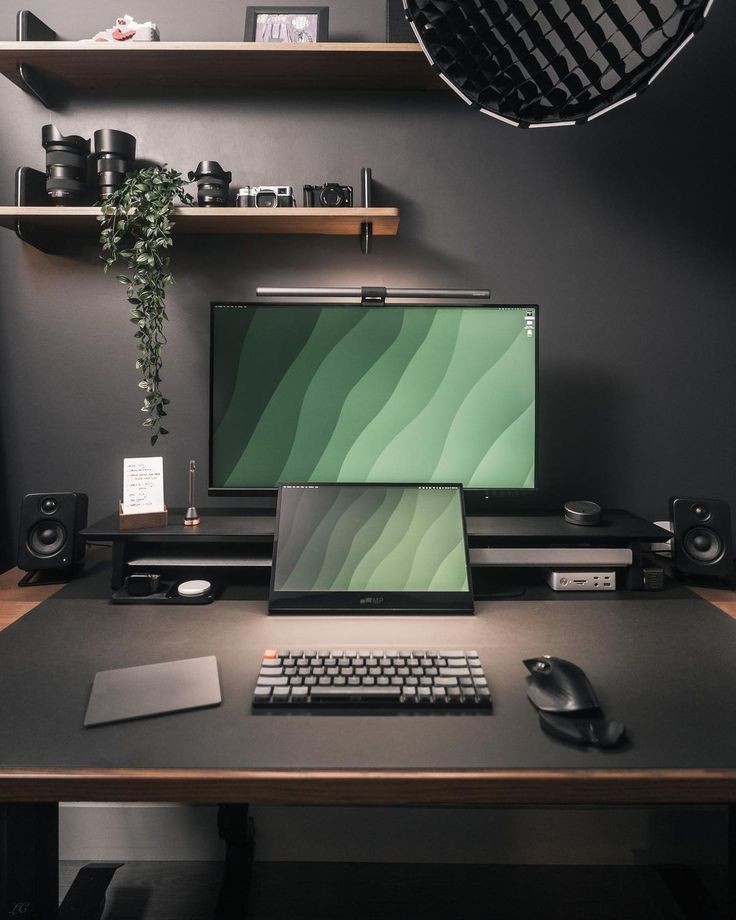 Modern workspace with dual monitors, keyboard, mouse, and camera equipment on shelves.